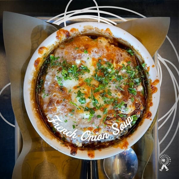 Oddfellows' French onion soup in a white bowl, topped with melted cheese and fresh parsley.