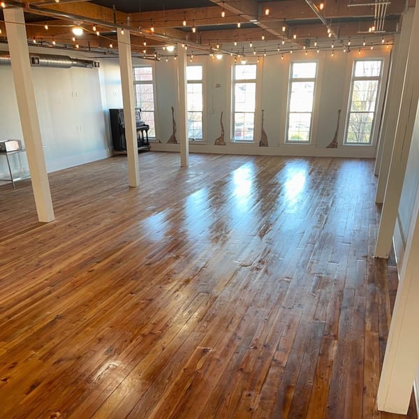 Spacious Oddfellows dining room with string lights, large windows, and polished wooden floors.