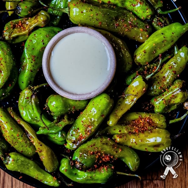 Oddfellows' blistered shishito peppers with chili flakes and a side of creamy dipping sauce.
