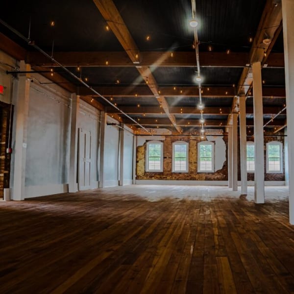 Oddfellows' spacious dining area features exposed brick, large windows, and string lights on a dark ceiling.