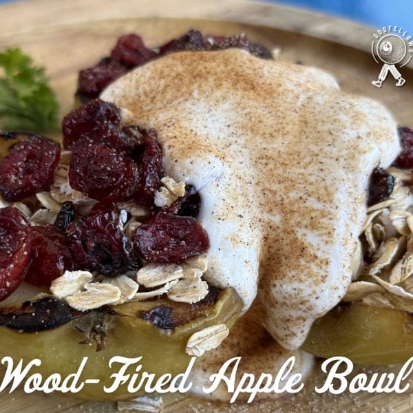 Close-up of a wood-fired apple bowl with cranberries, oats, and a dollop of cream.