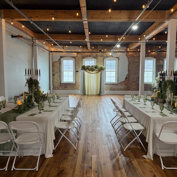 Oddfellows' rustic event space with long tables set for dining, exposed brick, and string lights.